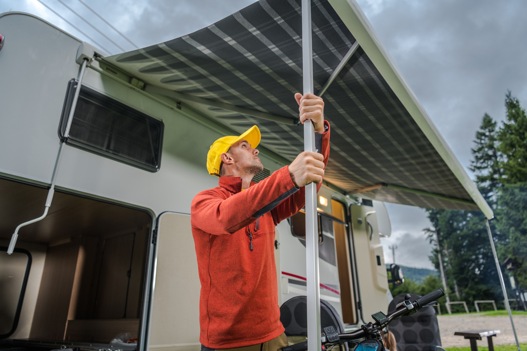 Man opening travel trailer awning to air out.