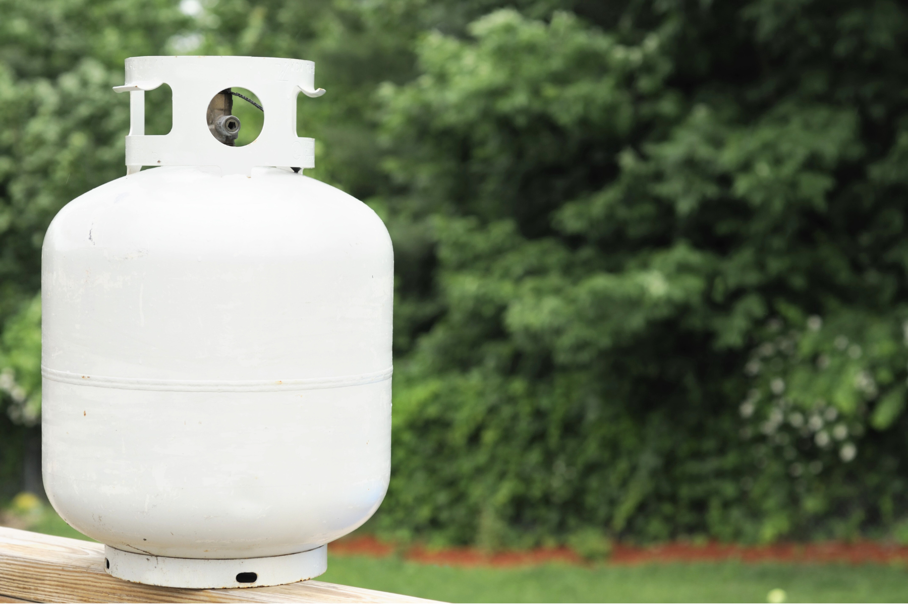 Travel trailer propane tank sitting on a wood table in a park