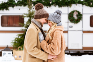 A couple embracing in front of their RV trailer in winter