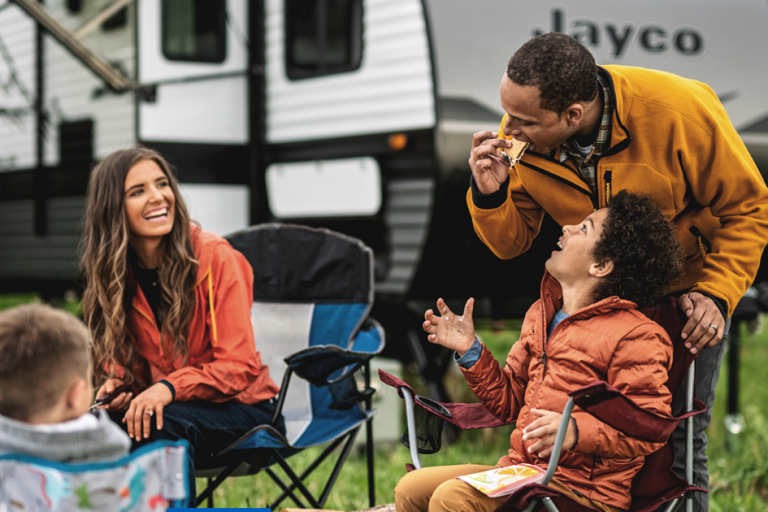 Family enjoying s'mores by the fire outside their Jayco travel trailer