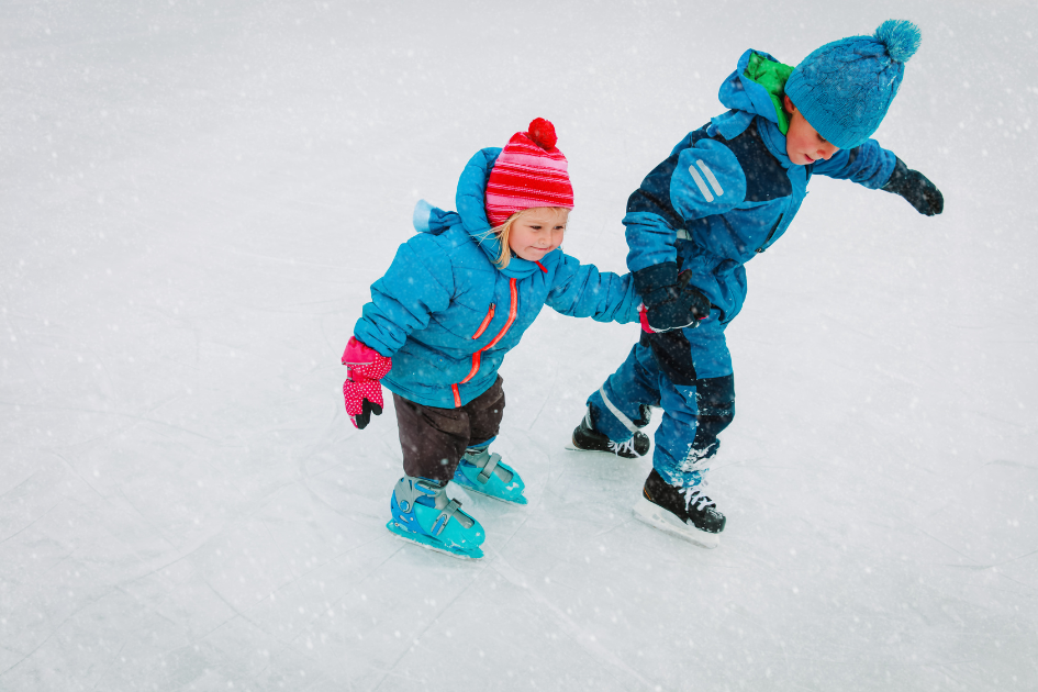 Two children ice skating had in hand