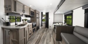 A panoramic shot of an RV's interior living area, including a spacious and beautiful kitchen, a sofa, and a dinette.